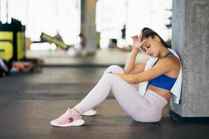 jeune femme en bonne santé assise détendue après une formation en salle de sport. photo