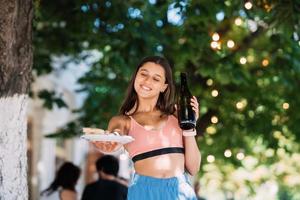 jeune femme porte une assiette de collations et une boisson dans les mains photo