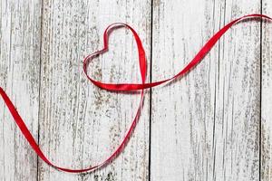 Joyeuse saint Valentin. Coeur de ruban rouge sur fond de bois blanc photo
