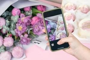 photo au téléphone de cupcakes fraîchement et de belles fleurs sur une table.