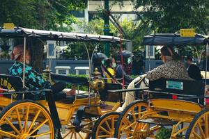 vue latérale de l'interaction des conducteurs de wagon ou d'andong sur jalan malioboro, yogyakarta. avec des vêtements batik typiques javanais et des chapeaux blangkon photo