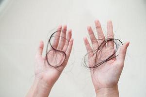 une femme asiatique a un problème avec la perte de cheveux longs attachée dans sa main. photo