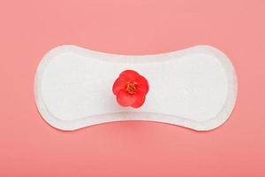 serviette hygiénique sur fond rose avec une fleur rouge. espace libre pour le texte. photo