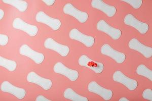 serviettes hygiéniques sur fond rose sous la forme d'un motif diagonal de répétitions, avec une fleur rouge sur le tampon. photo