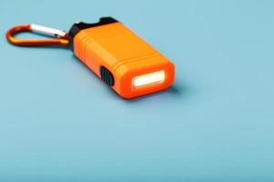lampe de poche led orange avec mousqueton sur fond bleu. lumières LED en vol. photo
