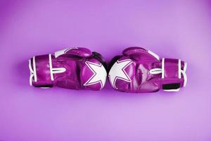 une paire de gants de boxe roses se font face sur un fond rose. photo