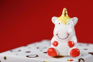 figurine licorne sur une boîte cadeau sur fond rouge avec espace libre. photo