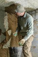 un homme jette du mortier de béton sur le mur, la première couche de plâtre sur le mur, des travaux de réparation en ukraine. photo