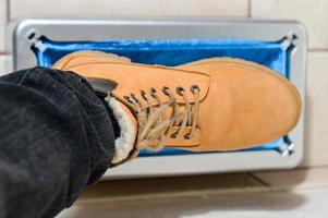 dispositif d'habillage automatique des couvre-bottes, un homme en chaussures marron met des couvre-bottes. photo