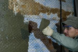 le maître jette une solution de béton liquide sur le mur, la première couche de plâtre sur le mur. photo