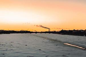 coucher de soleil orange dans une ville photographiée depuis une rivière glacée photo