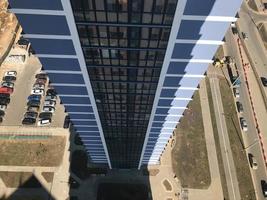 la vue depuis la hauteur du toit d'un grand grand bâtiment d'une maison de gratte-ciel sur la cour avec des voitures en face de l'autre bâtiment bleu du nouveau bâtiment photo