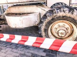 grandes roues puissantes avec bande de roulement et pneus de matériel de construction tout-terrain, tracteurs, voitures sur fond de ruban de protection rouge et blanc photo