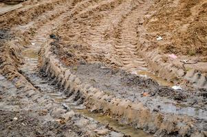 texture d'un chemin de terre sale et sale avec des flaques d'eau et de la boue de séchage d'argile avec des fissures et des ornières. hors route. l'arrière-plan photo