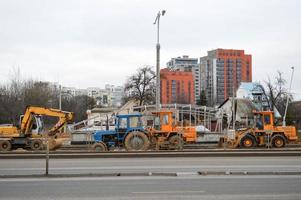 de nombreux équipements de construction spécialisés lourds industriels puissants de tracteurs excavateurs et de bulldozers effectuent des réparations routières lors de la construction d'un nouveau micro-quartier dans une grande ville photo