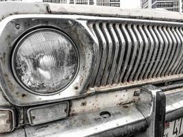 une ancienne calandre de radiateur argent métallisé chromé oxydé rouillé hipster vintage rétro et un projecteur rétro rond en verre d'une voiture américaine blanche blanche antique des années 60, 70, 80, 90, 2000 photo