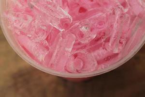 vue de dessus en gros plan glace de lait sucré aux fraises rose dans une tasse à emporter. photo