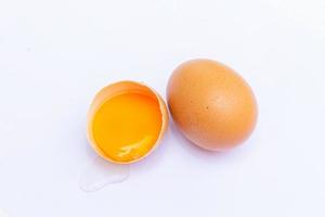 deux œufs bruns avec un œuf cassé en deux, avec un jaune à l'intérieur de la coquille, posés sur un fond blanc photo