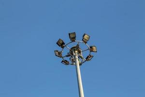un grand poteau électrique rempli de projecteurs dans le ciel bleu photo