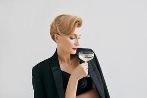 femme élégante et élégante mature en smoking avec un verre de vin mousseux. fête, célébration, concept anti-âge photo
