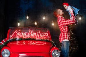 papa et sa fille dans le studio une nouvelle année. une fille à noël avec son père. Célébration du nouvel an. la famille près de la voiture rouge rétro est heureuse en hiver photo