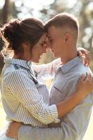 joyeuse jeune femme et homme s'embrassent à l'extérieur dans le parc d'été. rencontres et vacances romantiques. couple amoureux se regardant doucement par une journée ensoleillée. l'amour et les relations entre les jeunes photo