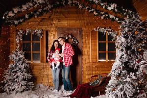 maman et papa posent avec leur charmante petite fille dans un studio de noël décoré. séance photo du nouvel an.