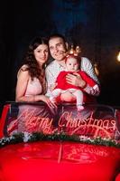 maman, papa et petite fille s'amusant dans la voiture rouge rétro de noël. parents avec une petite fille lors d'une séance photo de noël. tournage en studio avant les vacances.