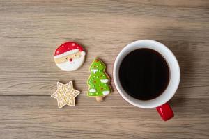 joyeux noël avec des biscuits faits maison et une tasse de café sur fond de table en bois. concept de veille de noël, fête, vacances et bonne année photo