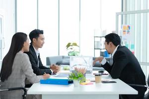 un groupe de jeunes entrepreneurs asiatiques. la haute direction se réunit pour examiner les données d'investissement en actions de l'équipe dans une salle de réunion à la lumière naturelle photo