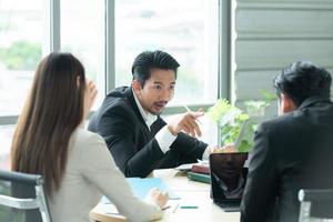 un groupe de jeunes entrepreneurs asiatiques. la haute direction se réunit pour examiner les données d'investissement en actions de l'équipe dans une salle de réunion à la lumière naturelle photo