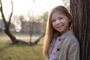 petite fille souriante à côté d'un arbre photo