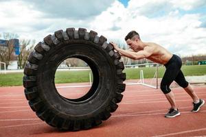 jeune homme poussant un pneu photo