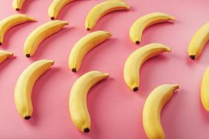 bananes jaunes éparpillées sur fond rose avec motif de texture photo