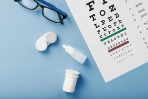 accessoires ophtalmiques lunettes et lentilles avec un tableau de test oculaire pour la correction de la vision sur fond bleu photo