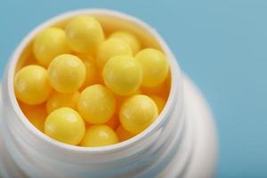 les vitamines sont jaunes dans un pot blanc sur fond bleu-bleu. photo
