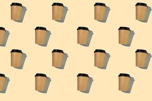 motif de tasses à café en carton avec un couvercle en plastique avec une ombre dure sur fond beige. le concept d'écologie, de recyclage, de protection de l'environnement. photo