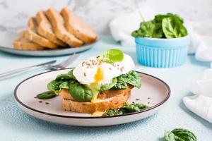 sandwich appétissant avec œuf poché, épinards et graines de lin sur une assiette. régime flexétarien. photo