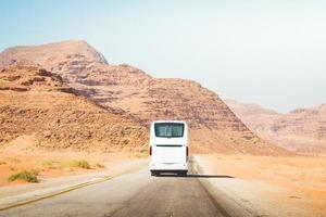 bus de ville blanc sur route goudronnée sur fond de montagnes pittoresques. excursions et service d'autocars express climatisation dans les destinations de voyage chaudes photo