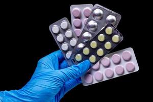 Pilules médicales sous blister sur fond noir isolé avec reflet dans la main photo