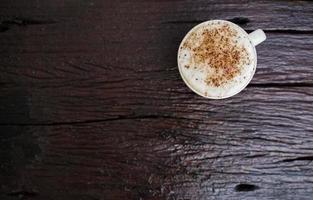 cappuccino chaud dans une tasse blanche avec fond en bois, le café est une boisson populaire dans le monde entier. photo