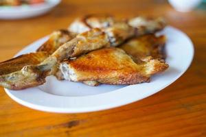 poulet grillé dans une assiette blanche sur parquet - menu thaïlandais traditionnel c'est un plat simple et populaire. photo