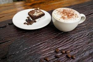 cappuccino chaud dans une tasse blanche avec fond en bois, le café est une boisson populaire dans le monde entier. photo