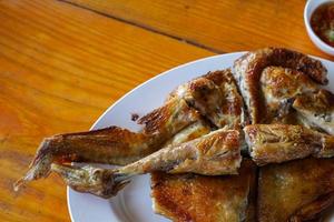 poulet grillé dans une assiette blanche sur parquet - menu thaïlandais traditionnel c'est un plat simple et populaire. photo