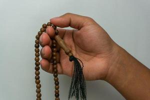 main tenant des perles de tasbih en bois isolées. perles de prière islamiques. concept de prière musulmane photo