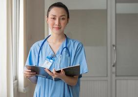 une femme médecin porte un uniforme et un stéthoscope lisant un document d'informations sur le patient pour une consultation chirurgicale. infirmière professionnelle asiatique travaille comme consultation de soins de santé à l'hôpital photo