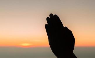 concept chrétien adorer ou prier dieu. silhouette d'homme chrétien avec amour, foi, dévotion à dieu avec fond de ciel de lever de soleil.dieu de culte masculin pour la paix, la victoire, le succès avec espoir. la religion photo