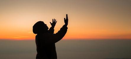 concept chrétien adorer ou prier dieu. silhouette d'homme chrétien avec amour, foi, dévotion à dieu avec fond de ciel de lever de soleil.dieu de culte masculin pour la paix, la victoire, le succès avec espoir. la religion photo