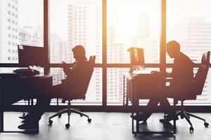 homme d'affaires silhouette au bureau travaillant au bureau côté fenêtres avec vue sur la ville urbaine photo