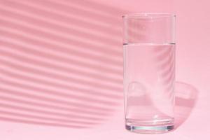 verre d'eau sur fond rose photo